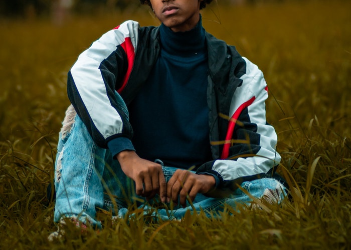 a black teen sitting on the grass